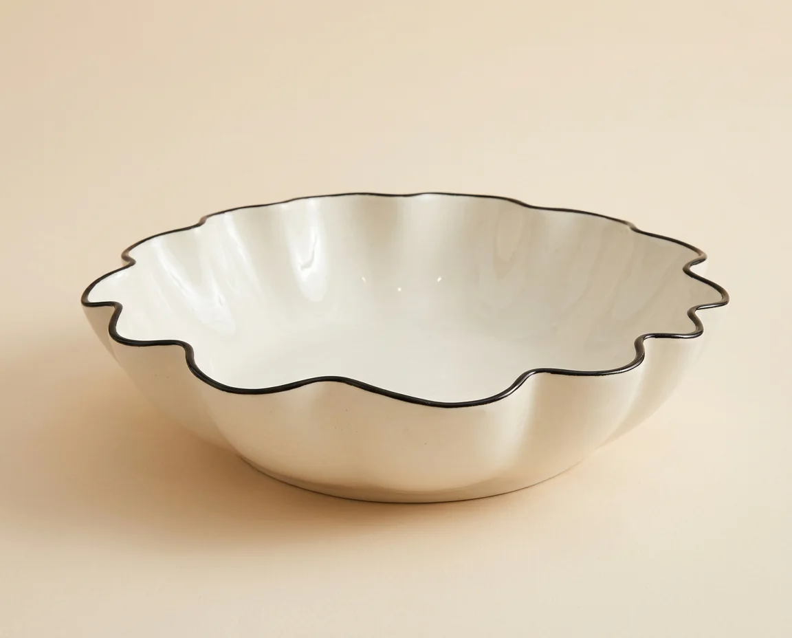 Hand-thrown ivory ceramic serving bowl with a black scalloped rim